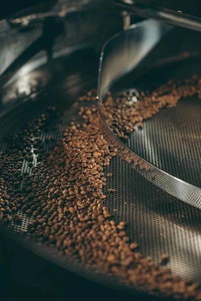 Vista de cerca de granos de café tostado en la máquina - foto de stock