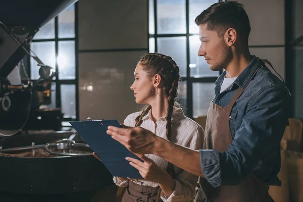 Portrait of coffee shop workers checking coffee beans roasting process together — Stock Photo