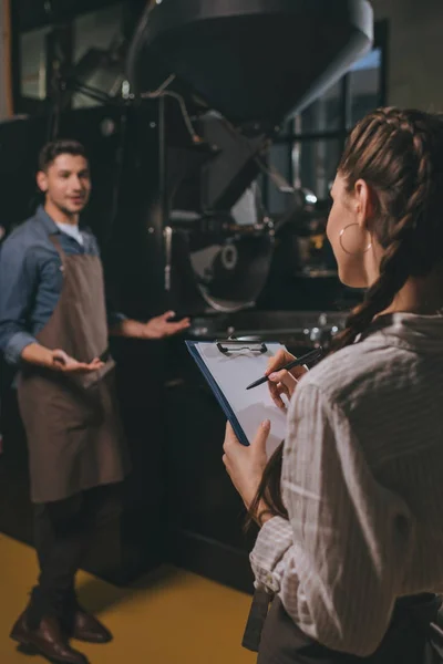 Messa a fuoco selettiva della donna controllo colleghi di lavoro durante il processo di torrefazione del caffè — Foto stock