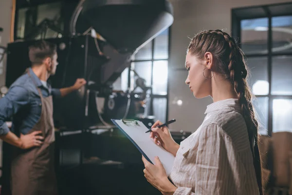 Вибірковий фокус жінки-перевірки колег працює під час процесу обсмажування кави — стокове фото