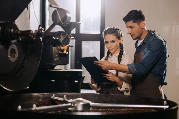 Coffeeshop-Mitarbeiter überprüfen gemeinsam den Röstprozess von Kaffeebohnen — Stockfoto