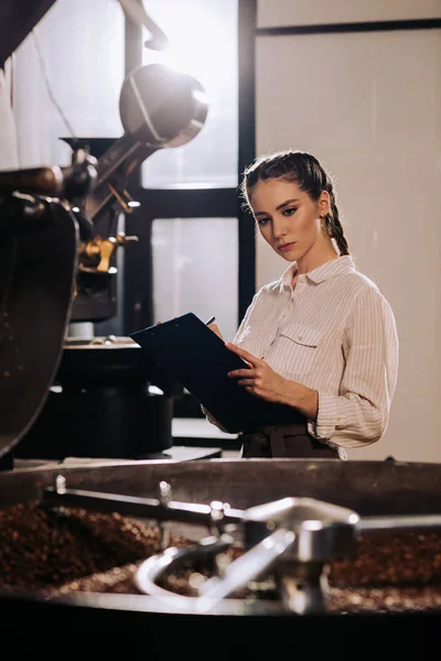 Портрет сфокусированного кофе жаровня с блокнотом проверки работы — стоковое фото