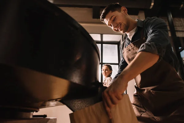 Coffee roaster roasting coffee beans in roasting machine with colleague near by — Stock Photo