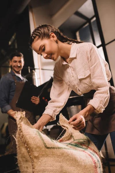 Side view of smiling woman tying sack bag with string — Stock Photo