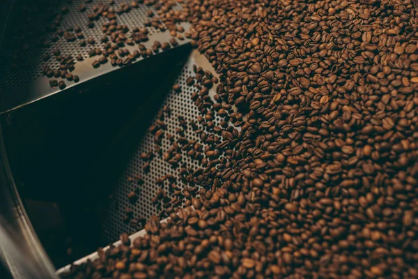 Vista de cerca de granos de café tostado en la máquina - foto de stock
