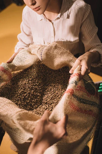 Recortado disparo de los trabajadores sosteniendo saco bolsa con granos de café juntos - foto de stock