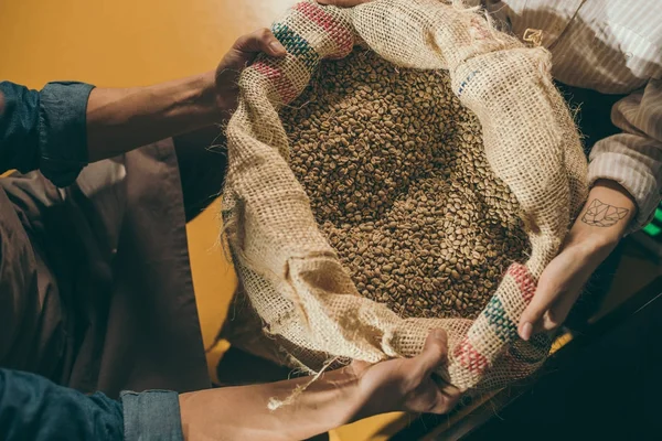 Plan recadré de travailleurs tenant sac avec grains de café ensemble — Photo de stock
