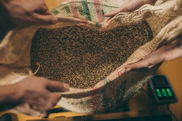 Plan recadré de travailleurs tenant sac avec grains de café ensemble — Photo de stock