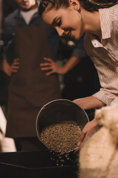 Foyer sélectif de la femme versant des grains de café dans la machine de torréfaction — Photo de stock