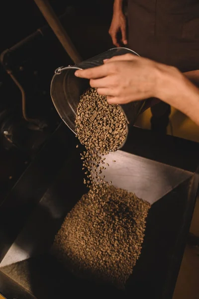 Teilansicht des Kaffeerösters, der Kaffeebohnen in Röstmaschine gießt — Stockfoto