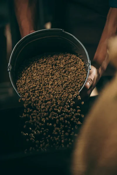 Vista parziale di torrefazione caffè versando chicchi di caffè in tostatrice — Foto stock