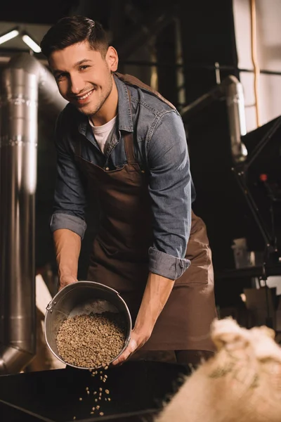 Coffee roaster pouring coffee beans into roasting machine — Stock Photo