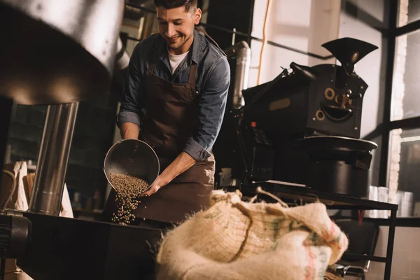 Tostador de café verter granos de café en la máquina de tostado - foto de stock