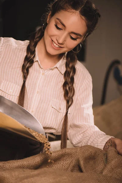 Portrait of smiling worker pouring coffee beans into sack bag — Stock Photo