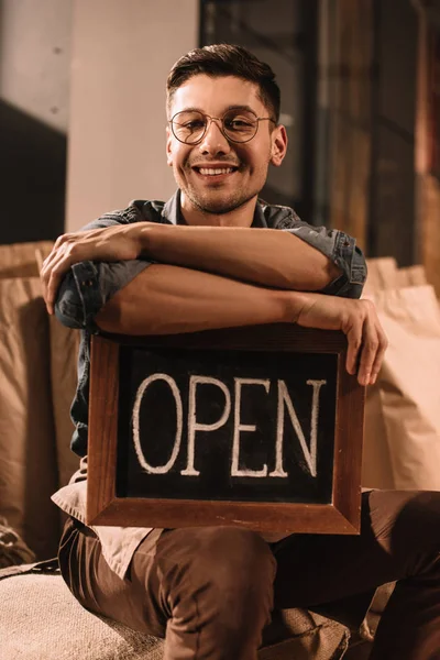 Retrato de trabalhador sorrindo café com sinal aberto olhando para a câmera — Fotografia de Stock