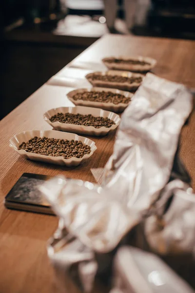Vue rapprochée des bols arrangés avec des grains de café pour la fonction alimentaire sur la table en bois — Photo de stock
