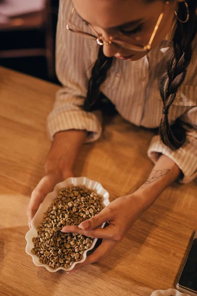 Blick von oben auf junge Frau, die Kaffeebohnen im Coffeeshop testet — Stockfoto