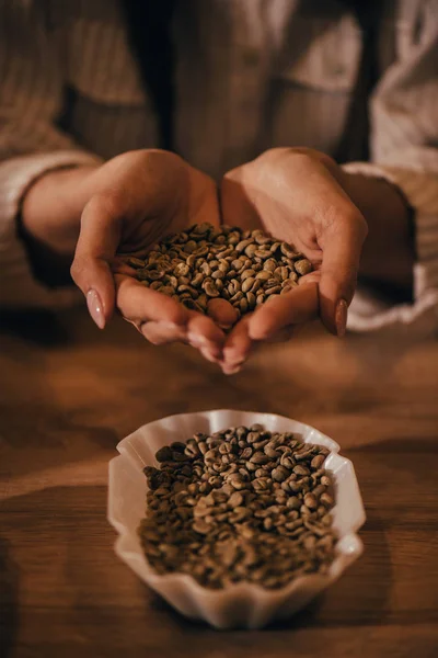 Messa a fuoco selettiva della donna che tiene i chicchi di caffè nelle mani — Foto stock