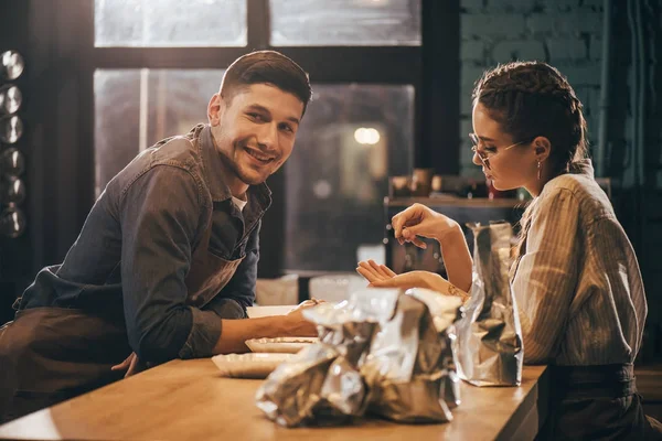 Jóvenes colegas de pie en la mesa de madera en la cafetería - foto de stock