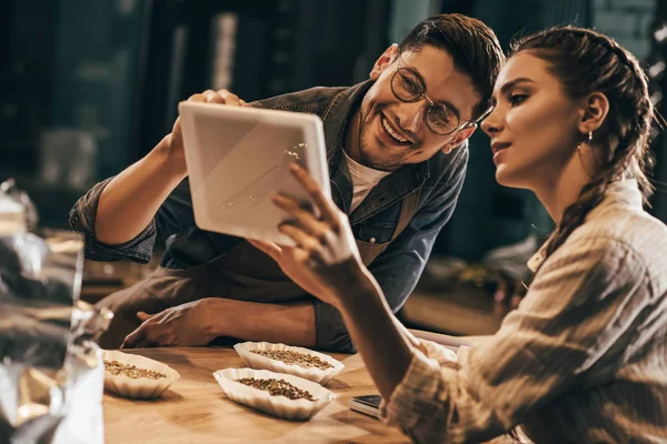 Portrait of young colleagues using tablet together in coffee shop — Stock Photo