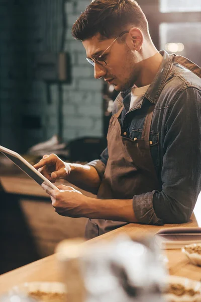 Visão lateral do trabalhador focado no avental usando tablet no café — Fotografia de Stock