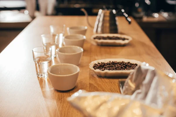 Vista de cerca de cuencos arreglados con granos de café y moler el café para la función de alimentos en la mesa de madera - foto de stock