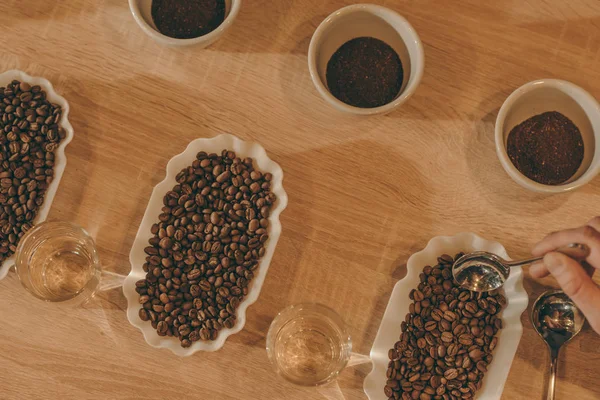 Tendido plano con tazones de café molido y granos de café para la función de alimentos en la superficie de madera - foto de stock