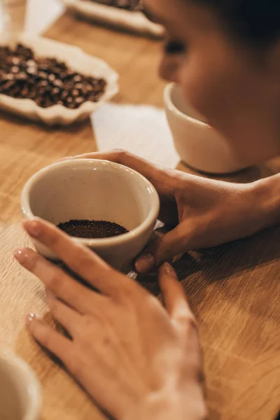 Colpo ritagliato di donna che tiene ciotola con macinare aromatico caffè in mano — Foto stock