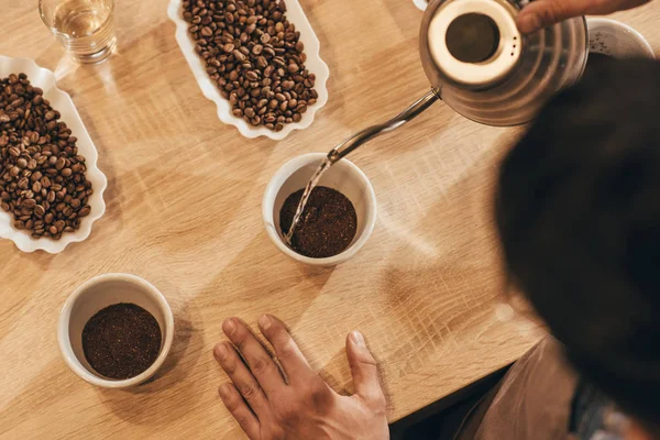 Vue aérienne de l'homme versant de l'eau chaude dans un bol avec du café moulu — Photo de stock