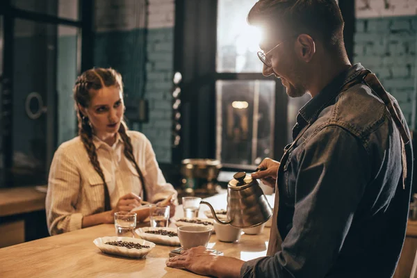 Mann gießt heißes Wasser in Schüssel mit gemahlenem Kaffee während Kaffeesatzleserei im Café — Stockfoto