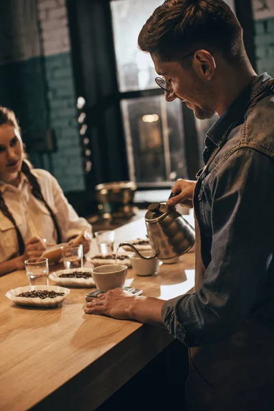 Человек наливая горячую воду в миску с молоть кофе во время функции кофе питание в кафе — стоковое фото