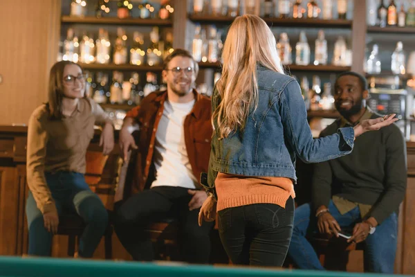 Vista trasera de la joven en el bar con amigos — Stock Photo