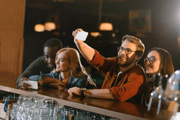 Companhia de jovens amigos atraentes tomando selfie no bar — Fotografia de Stock