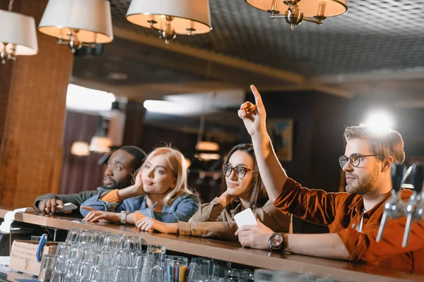 Giovani amici al bar chiamando barman — Foto stock