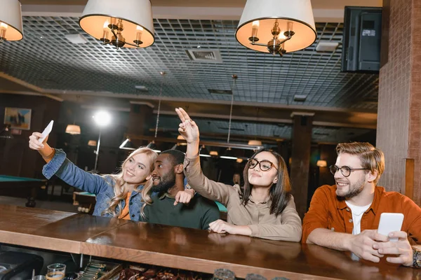 Jovens amigos alegres tomando selfie no bar — Fotografia de Stock