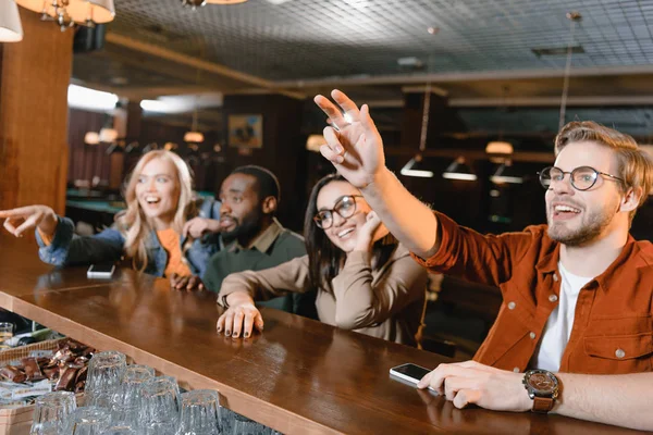 Young people at bar counter calling barman — Stock Photo