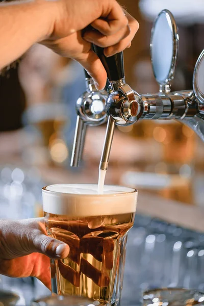 Abgeschnittenes Bild vom Barmann, der an der Bar Bier ins Glas gießt — Stockfoto
