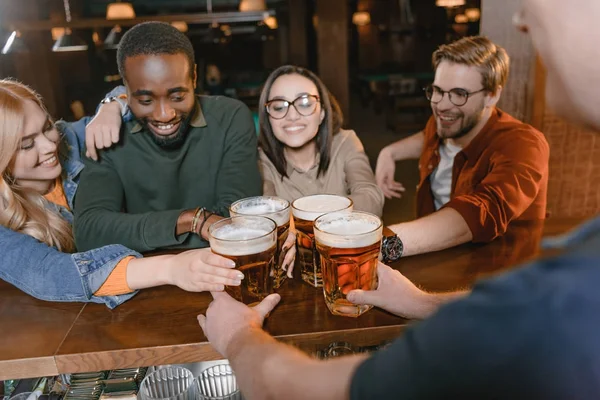 Cropped image of barman giving beer to multiculture company of friends — Stock Photo