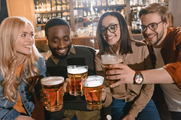 Весёлые мультикультурные друзья пьют пиво вместе в баре — стоковое фото