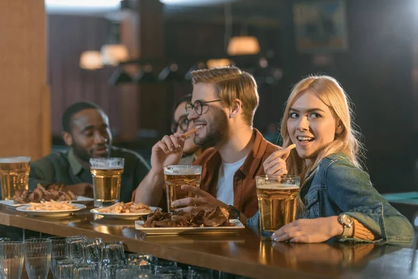 Attrayant amis multiculturels manger et boire au bar — Photo de stock
