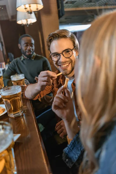 Amigos multiculturales atractivos comiendo y bebiendo en el bar — Stock Photo