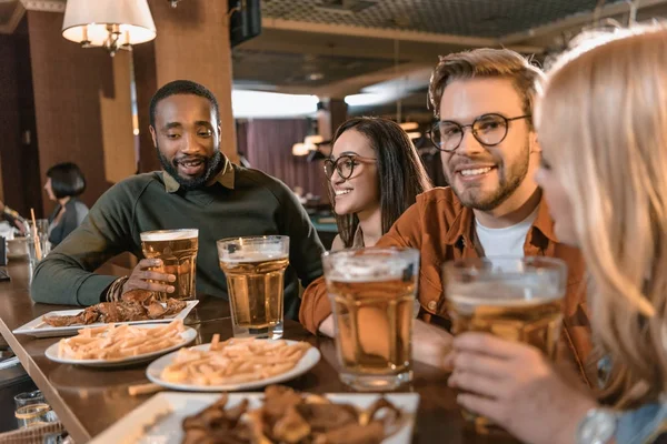 Joven empresa multicultural comer y beber en el bar — Stock Photo