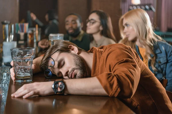 Очень пьяный молодой человек в баре с друзьями — стоковое фото