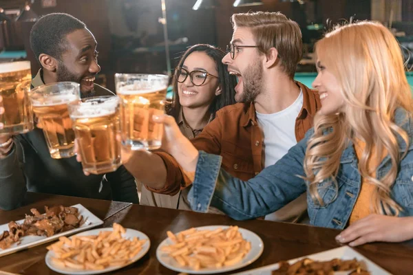 Young multiculture company eating and drinking at bar — Stock Photo