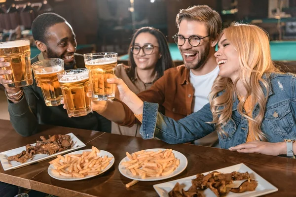 Young multiculture company eating and drinking at bar — Stock Photo