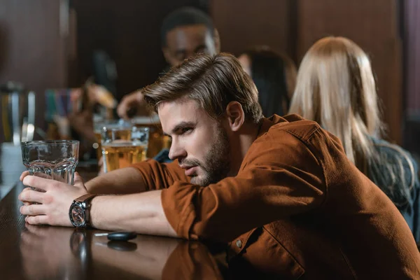 Very drunk caucasian man with automobile keys at bar with friends — Stock Photo