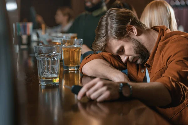 Very drunk caucasian man with automobile keys at bar with friends — Stock Photo