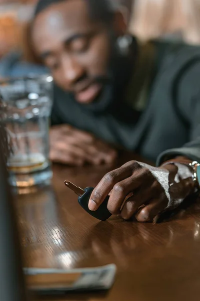 Hombre afroamericano muy borracho con llaves de automóvil en el bar - foto de stock