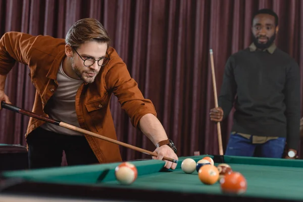 Handsome man playing in pool at bar with friend — Stock Photo