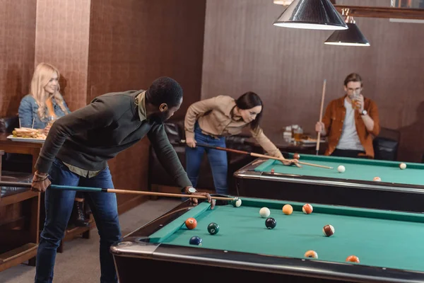 Young successful multiculture friends playing in pool at bar — Stock Photo